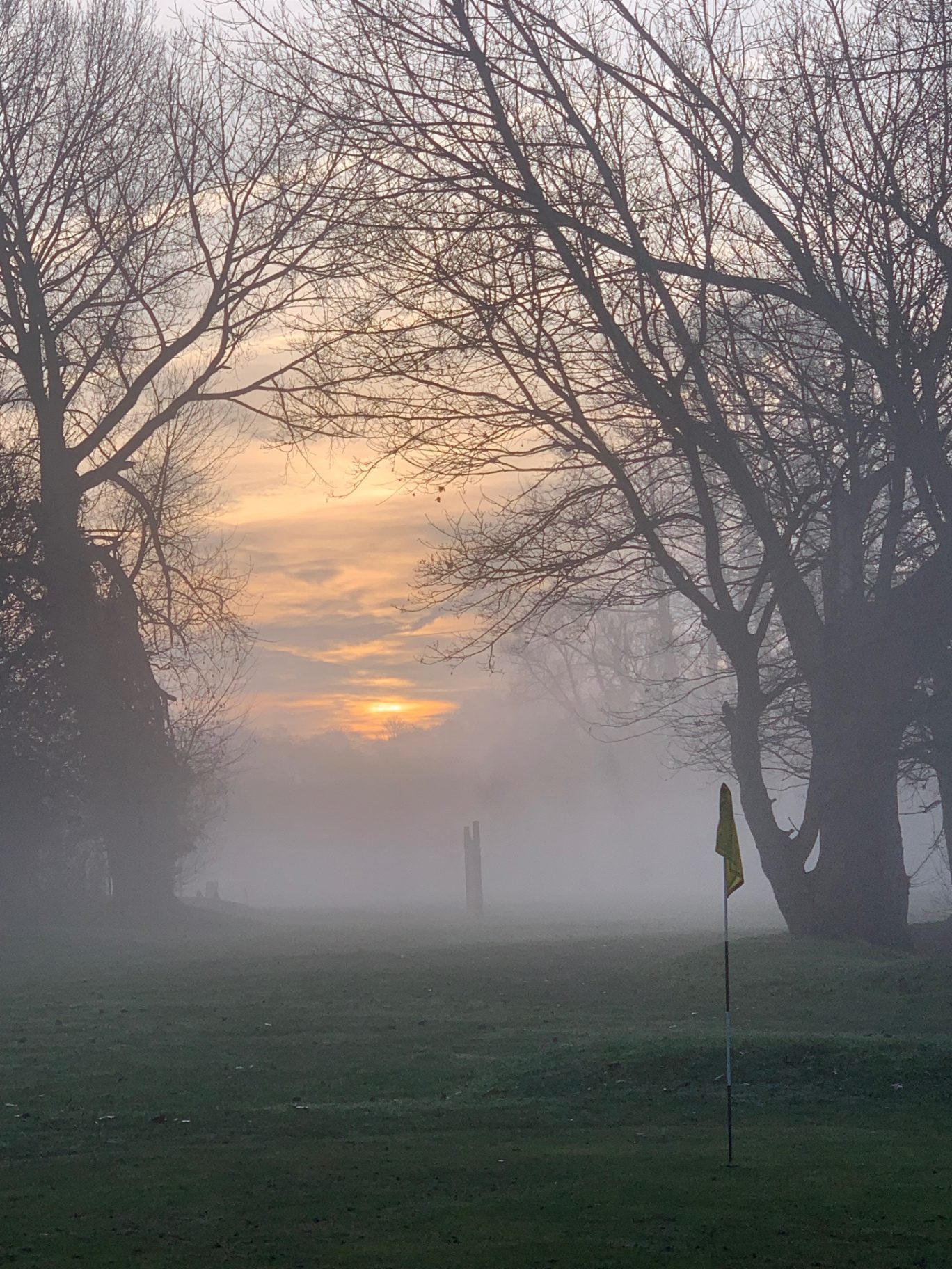 Misty winter sunrise behind the flag at Clare Park Lake